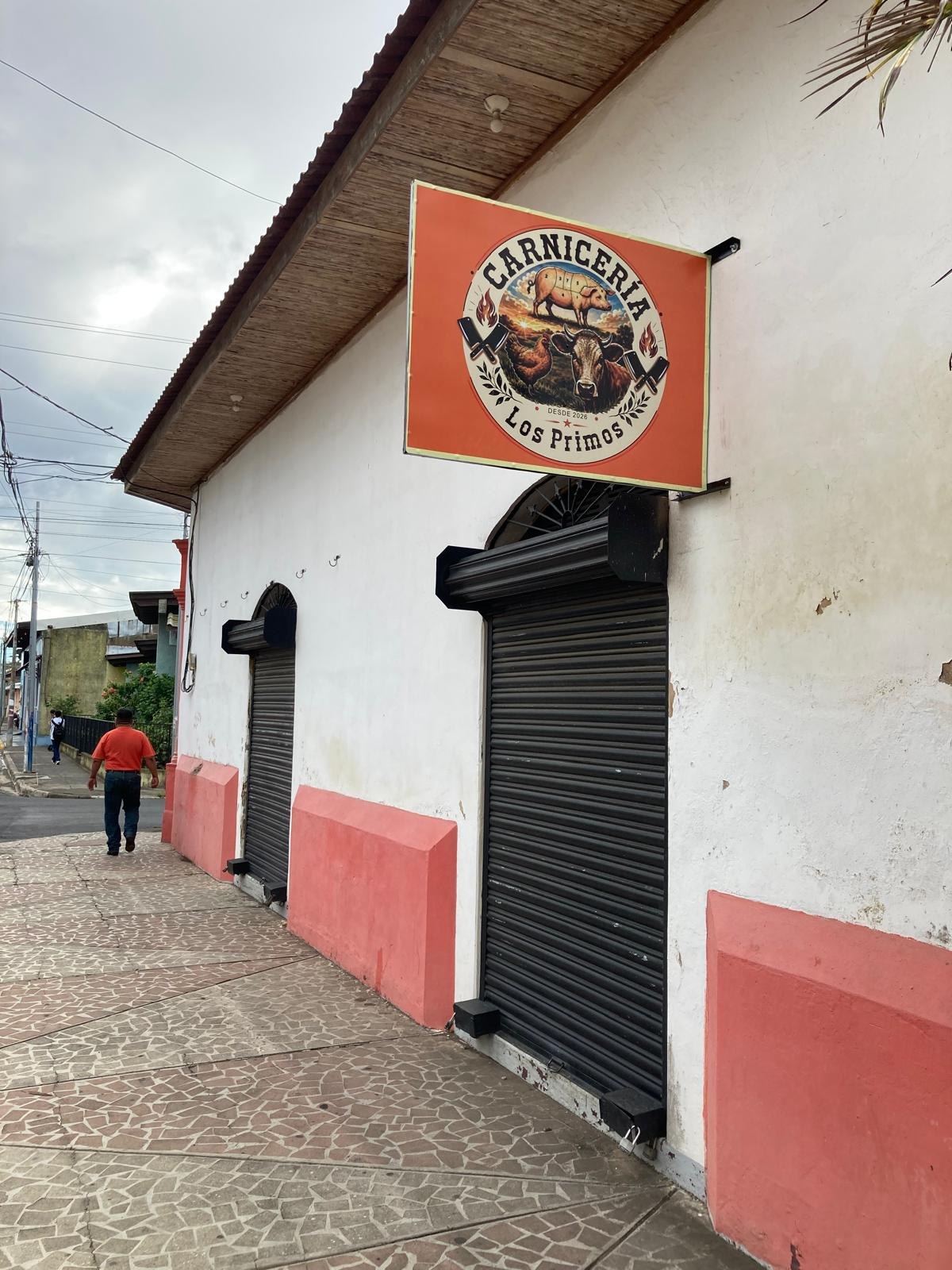 Fachada real de Carnicería Los Primos con su rótulo naranja